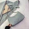 Bolso media luna de mezclilla azul claro con cadena plateada sobre fondo suave - Azul