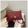 Detail of deep red woven texture on small shoulder bag with a gold rectangular buckle - Red