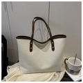 Dettaglio della trama intrecciata sulla borsa tote crema con manici marroni e rivetti - Bianco