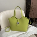 Bolso cubo verde lima en cuero con hebilla plateada sobre una silla beige moderna - Verde