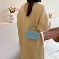 Light blue embossed mini box bag with chain strap and twisted handle carried by a model - Light Blue