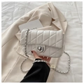 White quilted crossbody bag with silver chain strap and metal lock in a lifestyle setting - White
