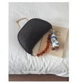 Detail of black woven handbag with gold chain, amber beads, and penguin plush charm - Black