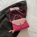 Magenta Umhängetasche mit gewebtem Deckel und goldener Schnalle auf schwarzem Blazer - Rosenrosa