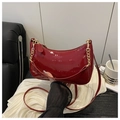 Gros plan du sac demi-lune en cuir verni rouge avec chaîne dorée et détails de texte - Rouge