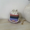 Detail der bunt gewebten Mini-Beuteltasche mit Perlengriff und goldener Kette - Lila