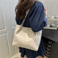 Cream white tote bag with geometric stitching and silver chain strap shown on shoulder - Beige Without Charm