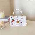 Detail van witte handtas met kersenprint, bloemsluiting en geweven handvat - Wit