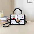 Detail van witte lederen tas met kersenprint, zwart handvat en gouden bloemslot - Zwart