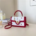 Detail van mini-tas met kersenprint, gedraaid handvat en gouden bloemsluiting - Rood