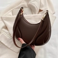 Brown half-moon underarm bag with pleated texture and golden hardware in lifestyle setting - Coffee