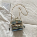 Detail of colorful woven bucket bag with large pearl buckle and gold chain strap - Blue