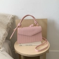 Chic pink woven crossbody bag with top handle and knot detail on a white magazine - Pink