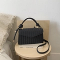 Detailed view of black woven texture crossbody bag with gold metal clasp and handle - Black