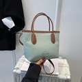 Bolso tipo cubo verde menta de cuero con asas marrones y logo plateado para oficina - Verde