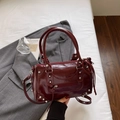 Vintage bordeauxrote Boston-Tasche mit Nieten und glänzender Oberfläche im Lifestyle-Look - Burgunderrot