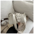 Detail of cream rectangular underarm bag with silver buckle on a stylish sofa - White