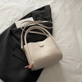 Chic cream white bucket bag with wave-edge design and adjustable strap on black blazer - White