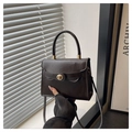 Détail du sac à main marron foncé en cuir synthétique avec fermoir rotatif doré et poignée - café