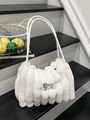 White faux fur shoulder bag with silver bow accent and leather strap on black stairs - White