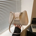 Elegant beige solid color shoulder bag with a gold bow detail and textured leather finish - White