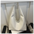 Gros plan du sac hobo blanc à texture tressée posé sur un siège en cuir noir élégant - Blanc