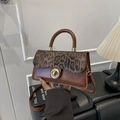 Brown leather crossbody bag featuring leopard print panels and golden metal twist lock - Brown
