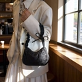 Elegante borsa a spalla nera con trama leopardata e fiocco indossata da una modella - Nero