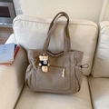 Bolso tote de pana marrón con bolsillos laterales y un oso decorativo en un sofá - Caqui (Con Colgante)