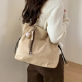 Detail view of beige suede shoulder bag with gold chain and baseball charm on model - Khaki With Braided Rope Baseball Charm