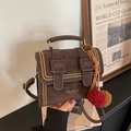 Dark brown matte Cambridge crossbody bag with gold rivet details and dual buckle straps - Coffee With Plush Ball Charm