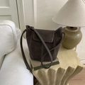 Dark brown bucket bag with contrast white stitching on books in a warm minimal interior - Coffee without Pendant