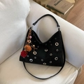 Schwarze Handtasche mit silbernen Ösen und Ethno-Anhänger auf weißem Sofa platziert - Schwarz Mit Plüschkugel-Anhänger