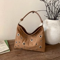 Close-up of brown suede shoulder bag featuring silver metal grommets on a wooden table - Brown - Without Pendant