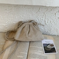 Beige pleated cloud crossbody bag in soft matte finish resting on an open vintage book - Off White