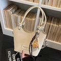 Cream bucket bag with knot handles, baseball charm, and adjustable crossbody strap - Beige with Baseball Charm