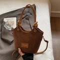 Brown frosted leather bucket bag with unique knotted handle on a white bedding backdrop - Brown No Pendant