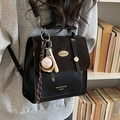 Vintage black leather backpack with flap buckle and baseball charm shown on model - Black With Baseball Pendant
