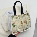 Crèmekleurige canvas tas met vintage bloemenprint en zwarte handvatten in lifestyle setting - Wit