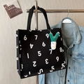 Große schwarze Canvas-Tasche mit weißen Zahlenprints und grünem Plüschanhänger - Mit Ornament / Schwarz