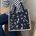 Graffiti canvas tote bag in black with LA print and khaki woven trim held by a model - Black Letter