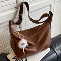 Brown lychee leather crossbody pillow bag with wide strap and fuzzy monster charm - Coffee with Pendant