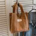 Chic brown canvas tote bag with fashion tag on casual denim jacket background - Brown