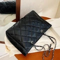 Klassieke zwarte gewatteerde leren crossbodytas met zilveren ketting op houten oppervlak - Zwart