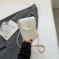 White lychee leather crossbody bag with gold round buckle and chain strap on a desk - Off White