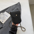 Elegant black pebble leather phone crossbody bag with gold chain strap on white bedding - Black