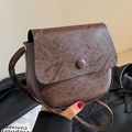 Retro bruine zadeltas van kunstleer met vintage textuur en enkele knoopsluiting - koffiekleur