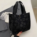 Black canvas tote bag featuring textured 3D floral patterns and a gold metal clasp - Small Black