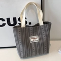 Vertical grey striped knit tote bag with thick cream straps and minimal patch detail - Gray