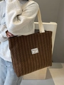 Braune Cord-Einkaufstasche mit weißen Baumwollträgern und Vintage-Label an einem Model - Braun